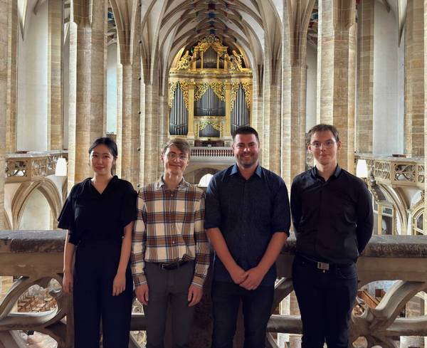 Daivd Kiefer mit den 3 anderen Preisträgern steht auf der Empore im Freiberger Dom. Dahinter ist die große Silbermann-Orgel zu sehen